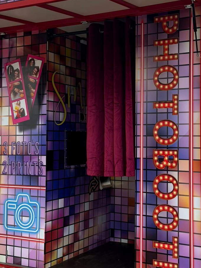 Binnenkant van de photobooth met gordijn, scherm en verlichte letters